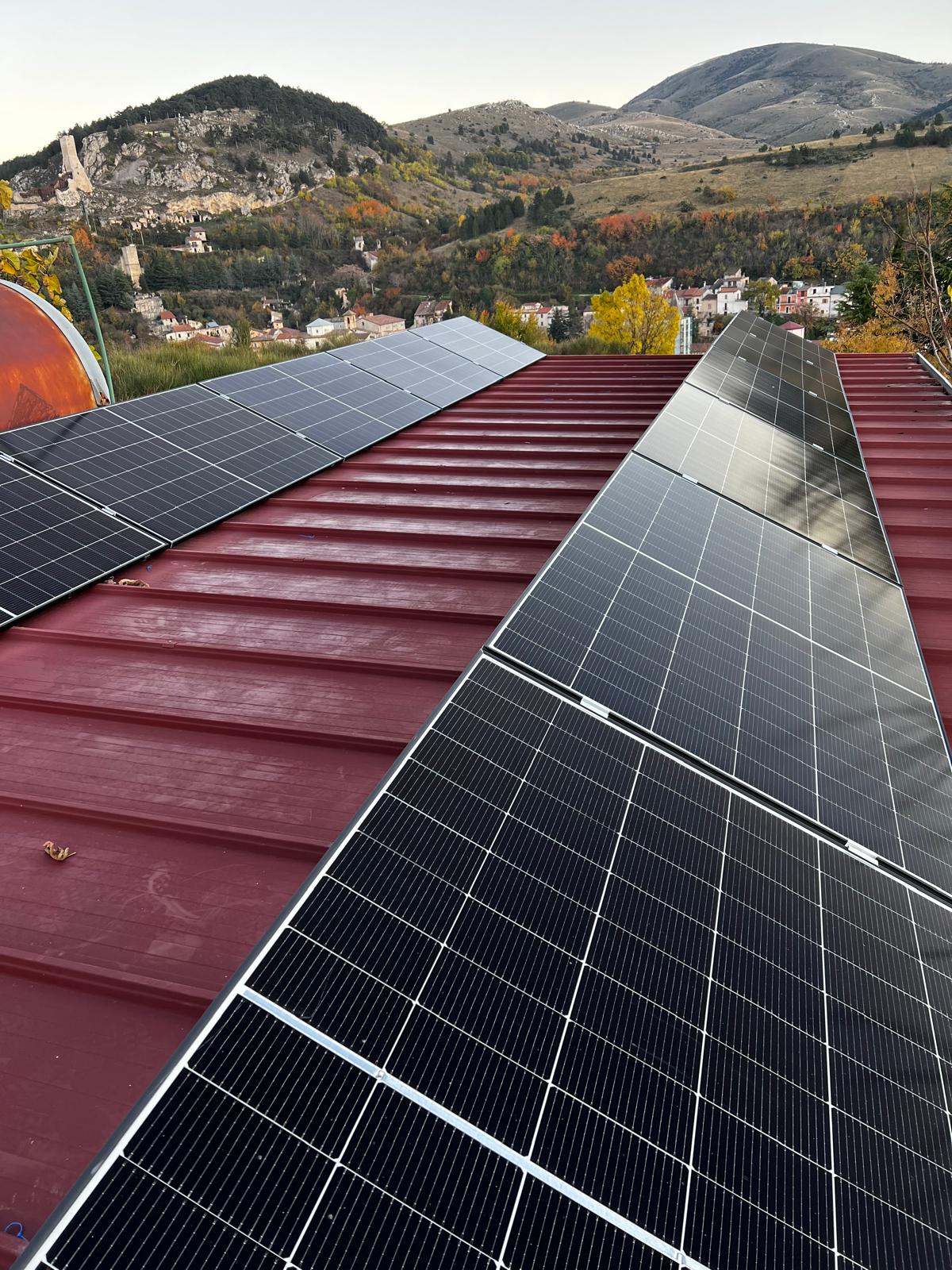 Pannelli fotovoltaici su tetto metallico rosso con panorama montano abruzzese - Parisse Impianti